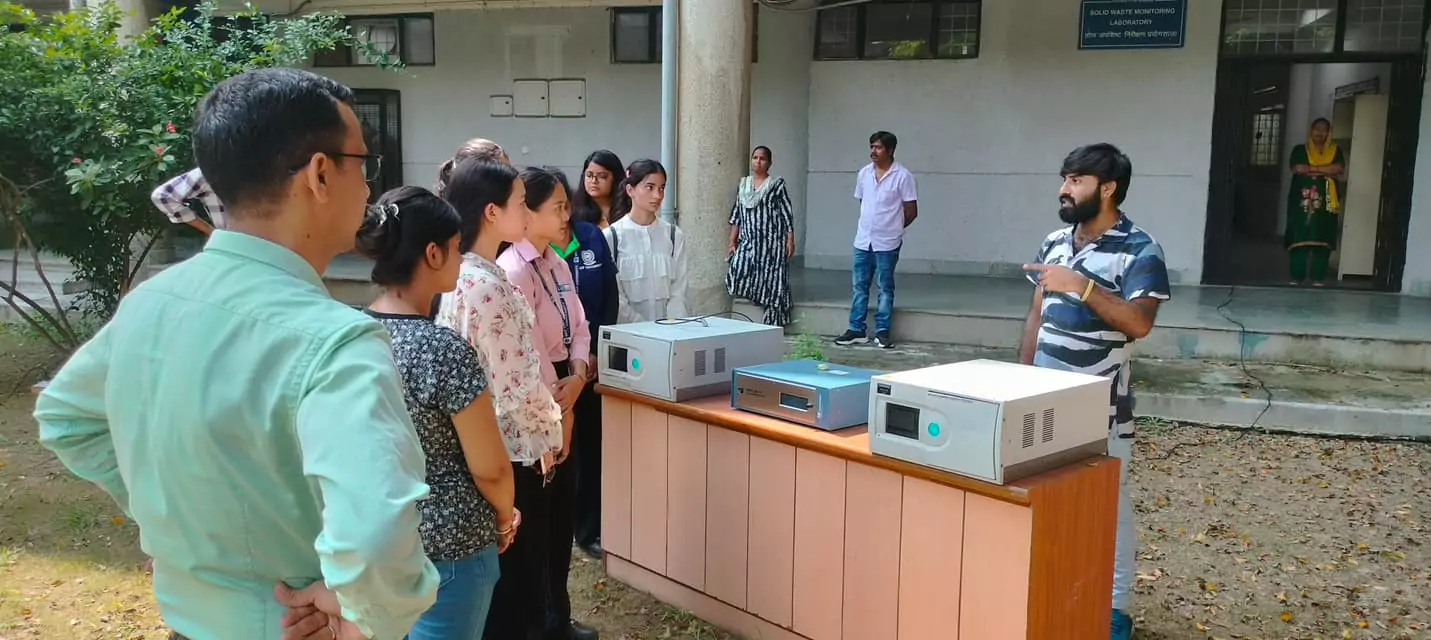 Students attentively learning about air quality monitoring instruments during an outdoor demonstration session — blending theory with real-world application